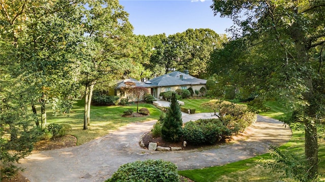 view of property's community with aphalt driveway and a yard