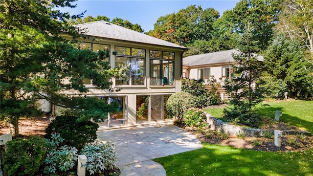 back of property featuring a patio, a lawn, and a sunroom