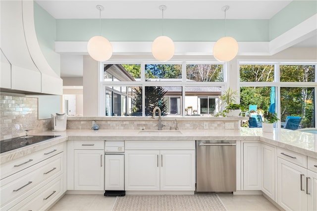 kitchen with tasteful backsplash, black electric stovetop, light stone countertops, white cabinets, and a sink