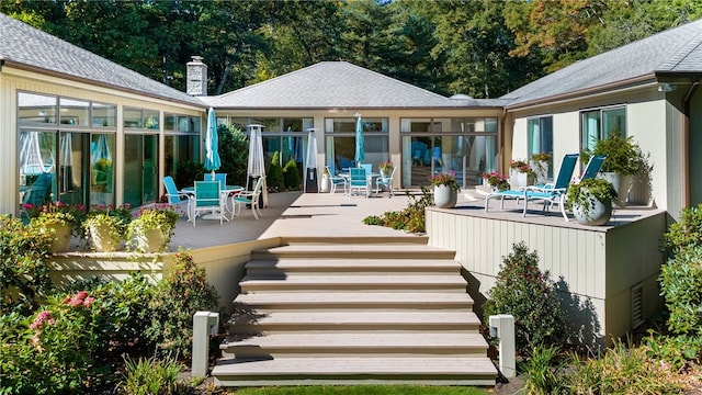 rear view of property with stairway, a wooden deck, and roof with shingles