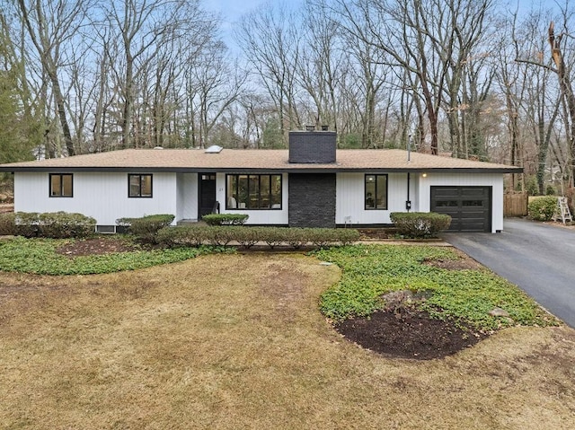 view of front of house with an attached garage, driveway, and a chimney