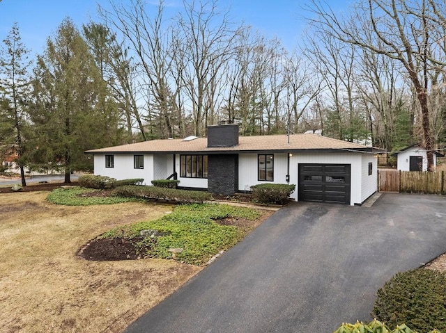 view of front facade featuring fence, a garage, driveway, and a chimney