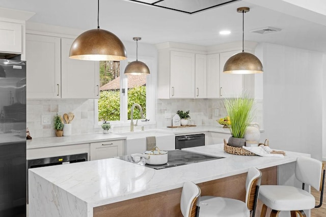 kitchen with a kitchen island, light stone counters, decorative backsplash, white cabinets, and black appliances