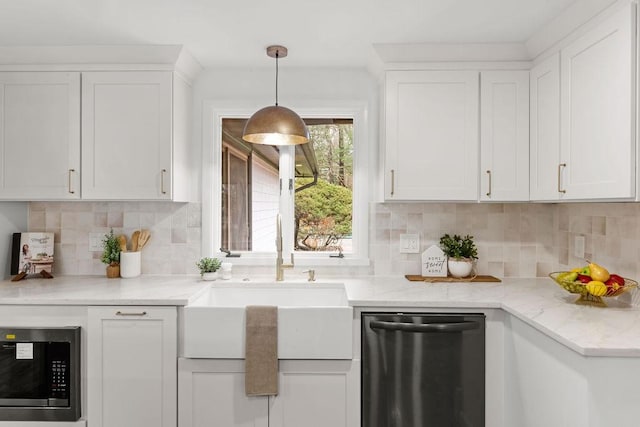 kitchen featuring a sink, stainless steel microwave, white cabinetry, dishwasher, and hanging light fixtures