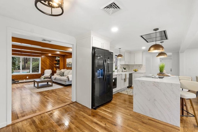 kitchen with light wood finished floors, visible vents, light countertops, and black refrigerator with ice dispenser