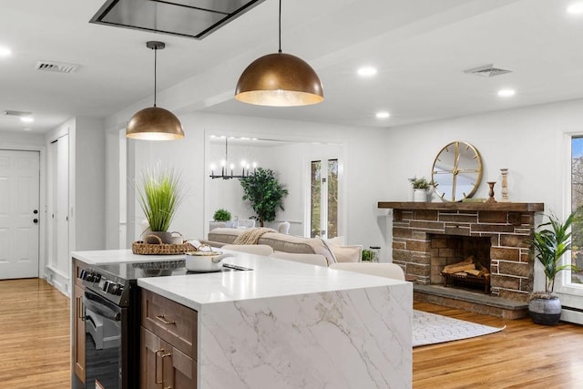 kitchen with light wood finished floors, visible vents, recessed lighting, a fireplace, and black / electric stove