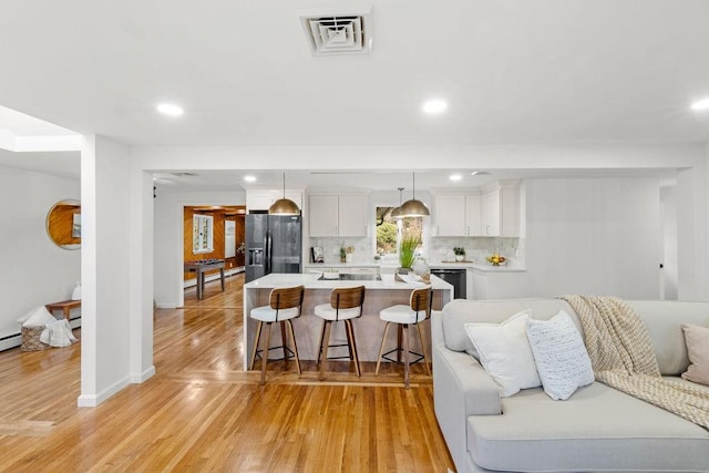 kitchen with fridge with ice dispenser, a kitchen bar, visible vents, light countertops, and decorative backsplash