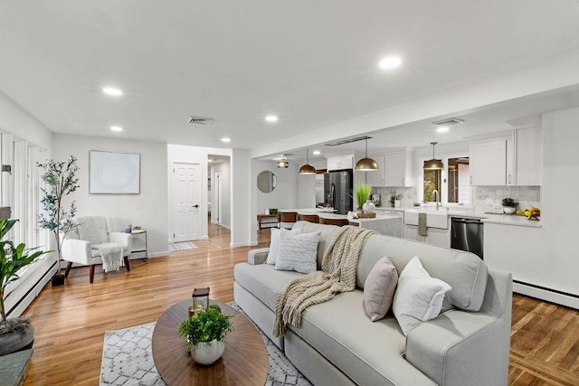 living room with a baseboard radiator, recessed lighting, visible vents, and light wood-type flooring