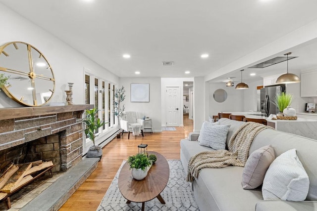 living room featuring recessed lighting, a fireplace, visible vents, and light wood finished floors