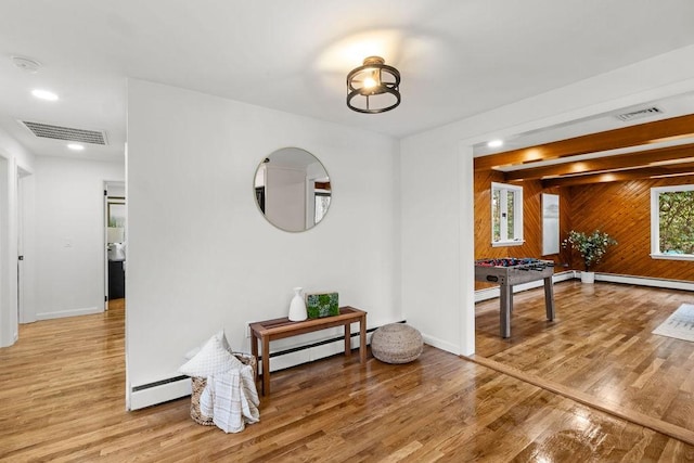 corridor featuring light wood-type flooring, baseboards, visible vents, and a baseboard radiator