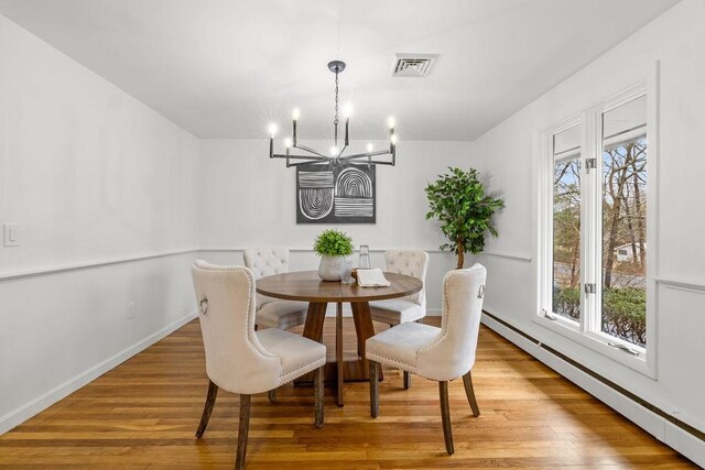 dining area featuring baseboards, wood finished floors, visible vents, and a baseboard radiator