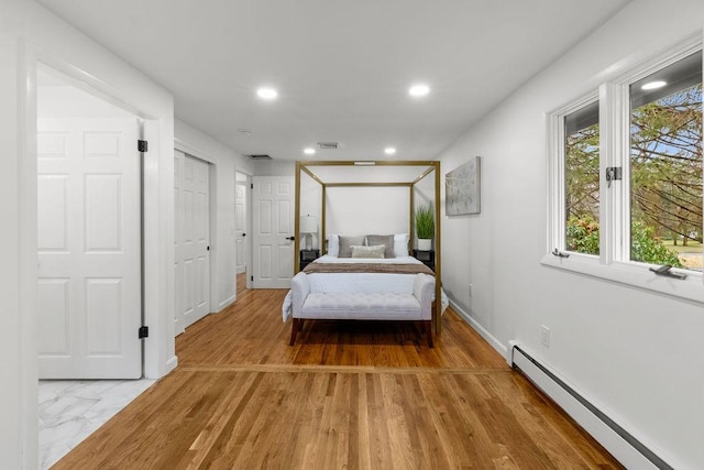 bedroom with light wood finished floors, visible vents, baseboards, recessed lighting, and a baseboard radiator