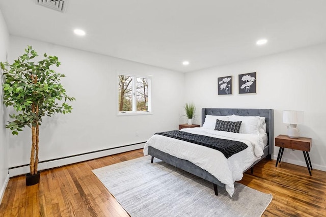 bedroom featuring hardwood / wood-style floors, recessed lighting, visible vents, and baseboard heating