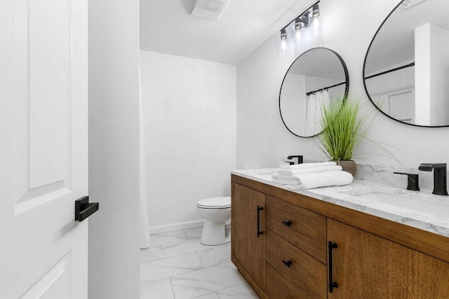 bathroom featuring toilet, marble finish floor, a sink, double vanity, and baseboards