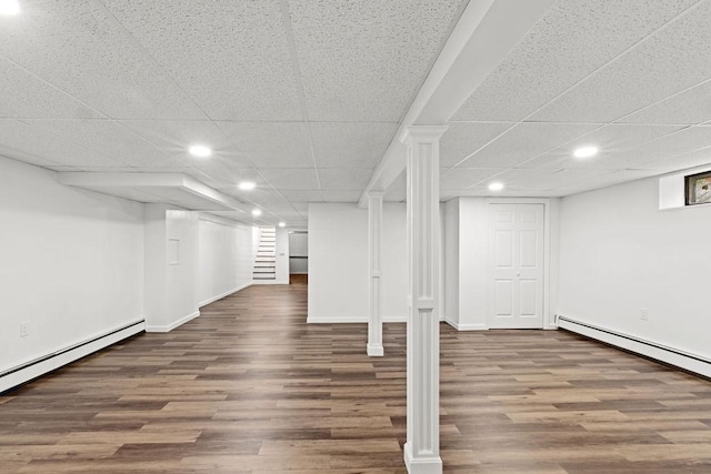 finished basement with stairs, wood finished floors, baseboards, and a baseboard radiator