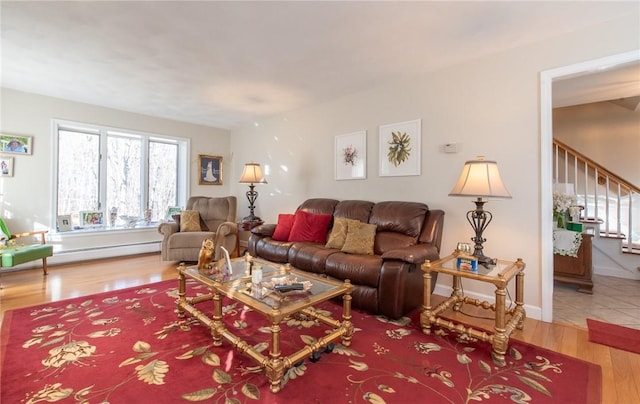 living area featuring stairway, baseboard heating, baseboards, and wood finished floors