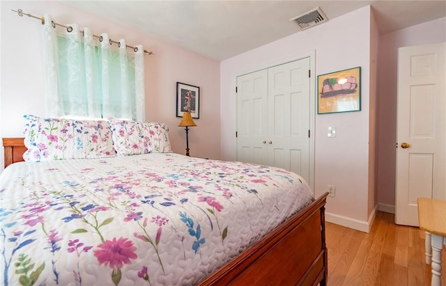 bedroom with light wood-style floors, visible vents, a closet, and baseboards