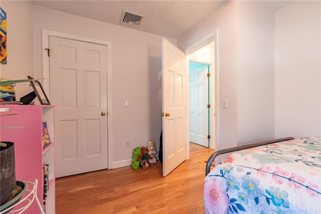 bedroom featuring baseboards, visible vents, and light wood finished floors