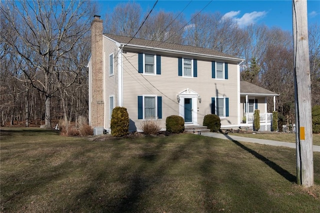 colonial-style house with a chimney and a front yard