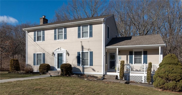 colonial home featuring a porch, a chimney, and a front lawn