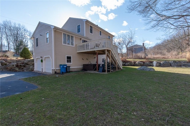 back of property with aphalt driveway, a wooden deck, stairs, a yard, and an attached garage