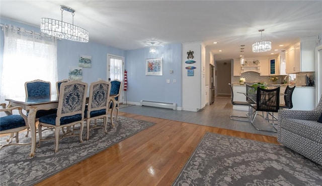 dining area with wood finished floors, baseboards, a baseboard radiator, recessed lighting, and a notable chandelier