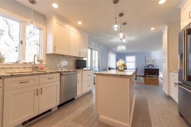 kitchen with a kitchen island, light wood-style flooring, white cabinets, appliances with stainless steel finishes, and tasteful backsplash