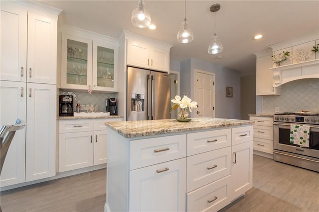 kitchen with a kitchen island, glass insert cabinets, decorative light fixtures, appliances with stainless steel finishes, and white cabinetry