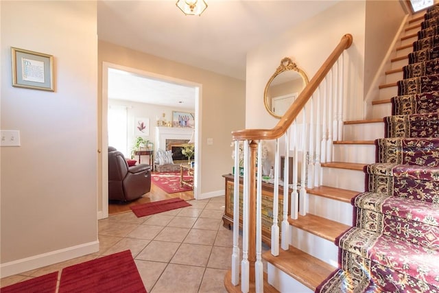 stairway featuring tile patterned floors, a fireplace, and baseboards