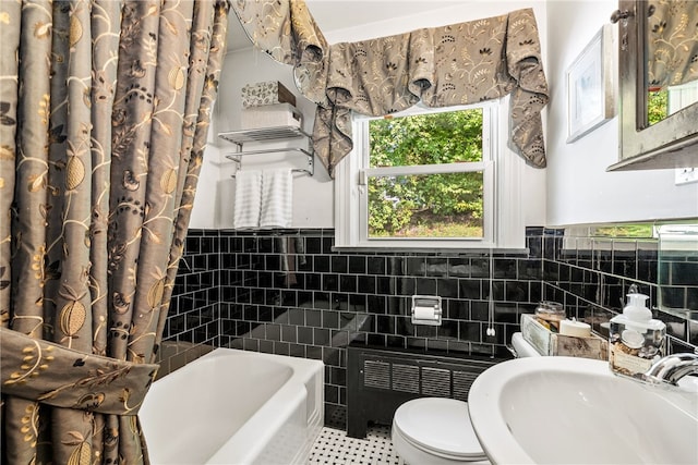 bathroom featuring a wainscoted wall, radiator heating unit, a sink, tile walls, and toilet