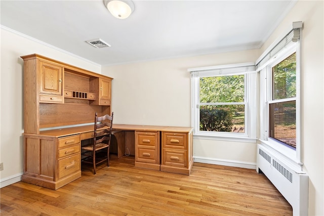 office space featuring light wood-type flooring, visible vents, ornamental molding, built in desk, and radiator heating unit