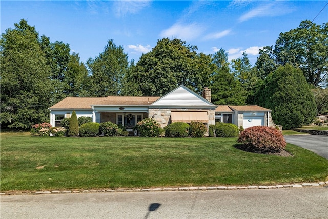 ranch-style house featuring a front yard, a chimney, driveway, stone siding, and an attached garage