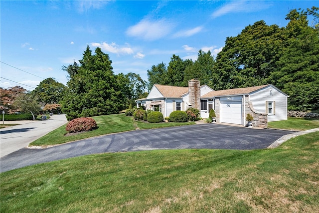 view of front of house with aphalt driveway, a front yard, an attached garage, and a chimney