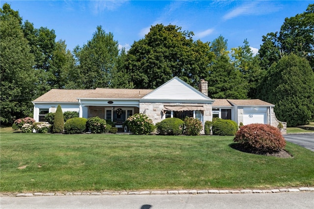 ranch-style home featuring a front lawn, an attached garage, driveway, and a chimney