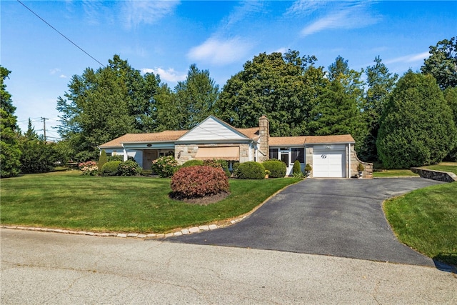 single story home featuring driveway, an attached garage, a chimney, a front lawn, and stone siding