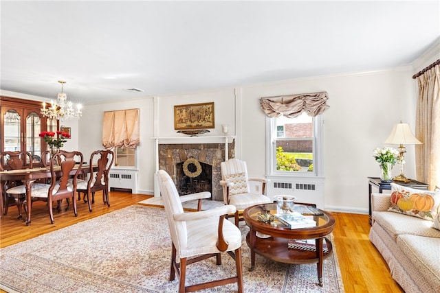 living area featuring a stone fireplace, light wood-style flooring, and radiator heating unit