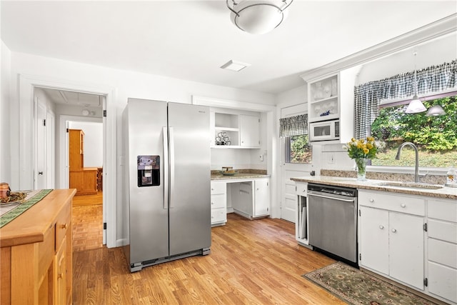 kitchen with open shelves, light wood-style flooring, appliances with stainless steel finishes, white cabinets, and a sink