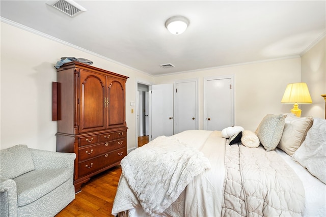 bedroom featuring visible vents, dark wood-type flooring, and ornamental molding