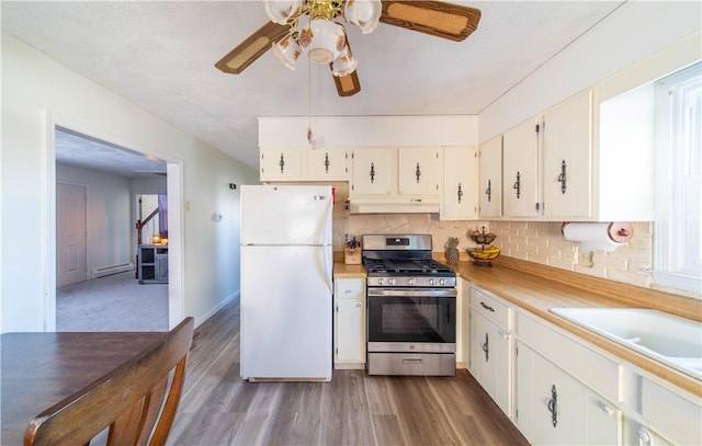 kitchen featuring stainless steel gas range oven, dark wood finished floors, under cabinet range hood, light countertops, and freestanding refrigerator