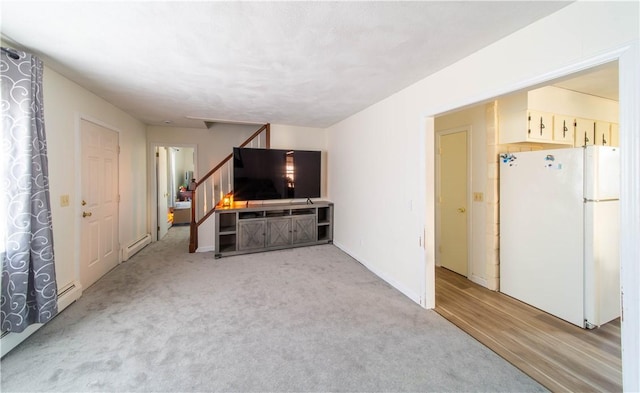 unfurnished living room with baseboard heating, light colored carpet, stairs, and baseboards