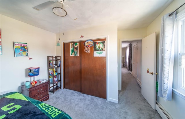 carpeted bedroom with a closet, a ceiling fan, and a baseboard radiator