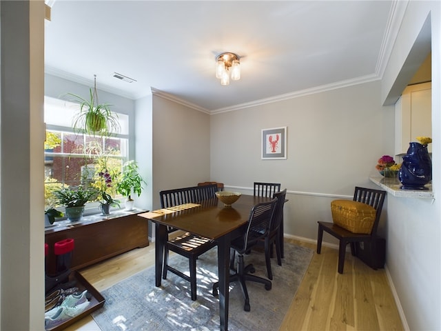 dining space featuring visible vents, baseboards, light wood-style floors, and ornamental molding