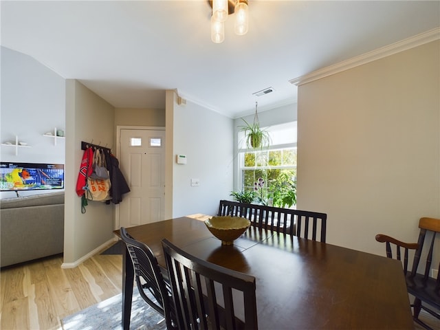 dining room featuring visible vents, baseboards, crown molding, and light wood finished floors