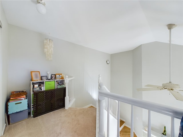 hallway with an upstairs landing, carpet, and vaulted ceiling