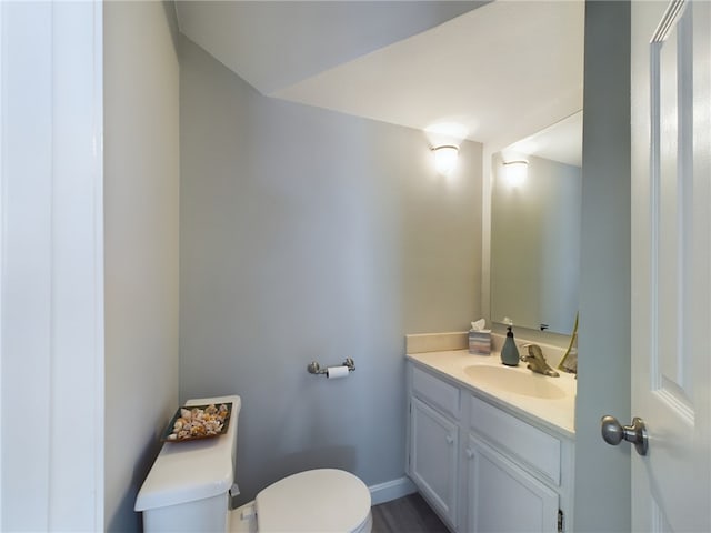 half bath with vanity, toilet, and baseboards