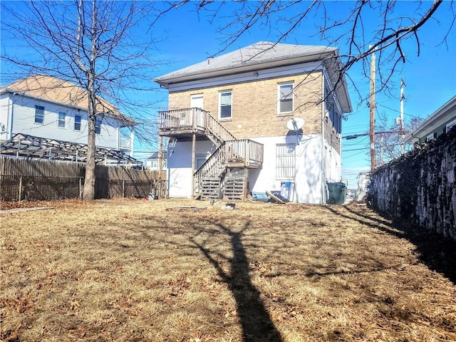 rear view of house with stairway, brick siding, and fence