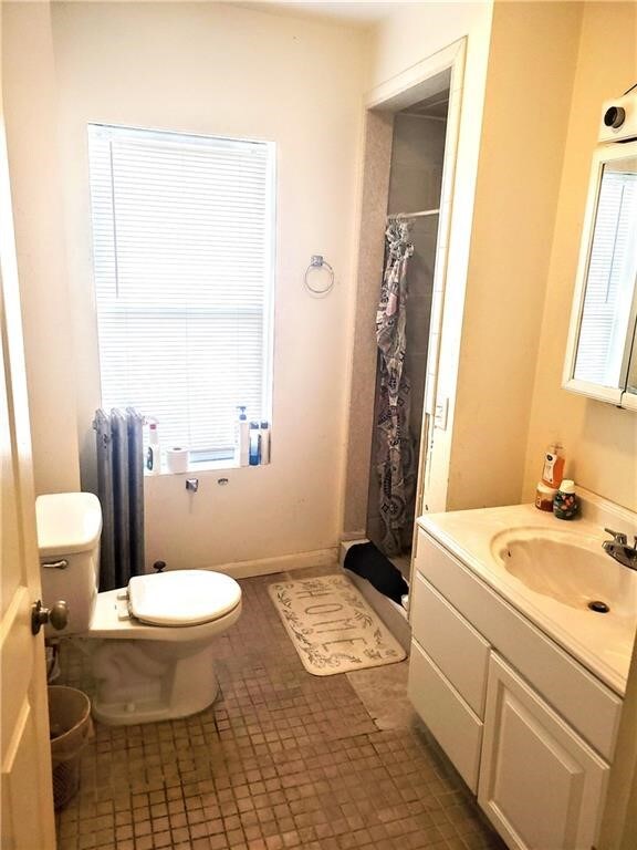 full bath with curtained shower, radiator heating unit, toilet, and vanity