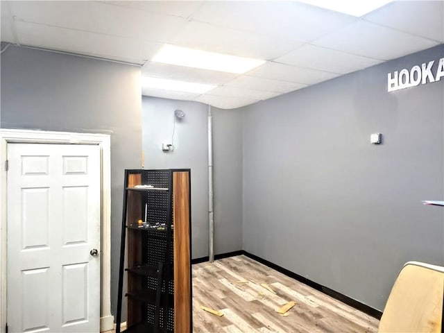 interior space with baseboards, a paneled ceiling, and light wood-style flooring