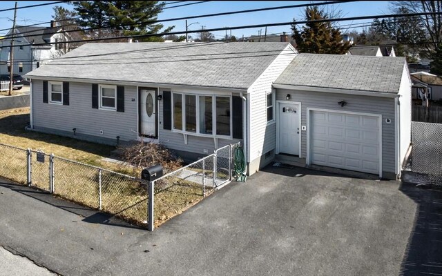 ranch-style house with a fenced front yard, a garage, aphalt driveway, and a shingled roof