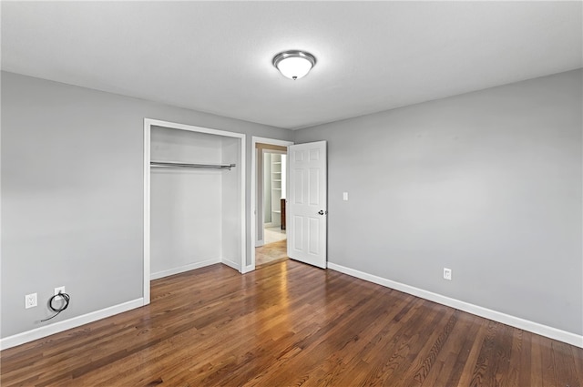 unfurnished bedroom with wood finished floors, a closet, and baseboards